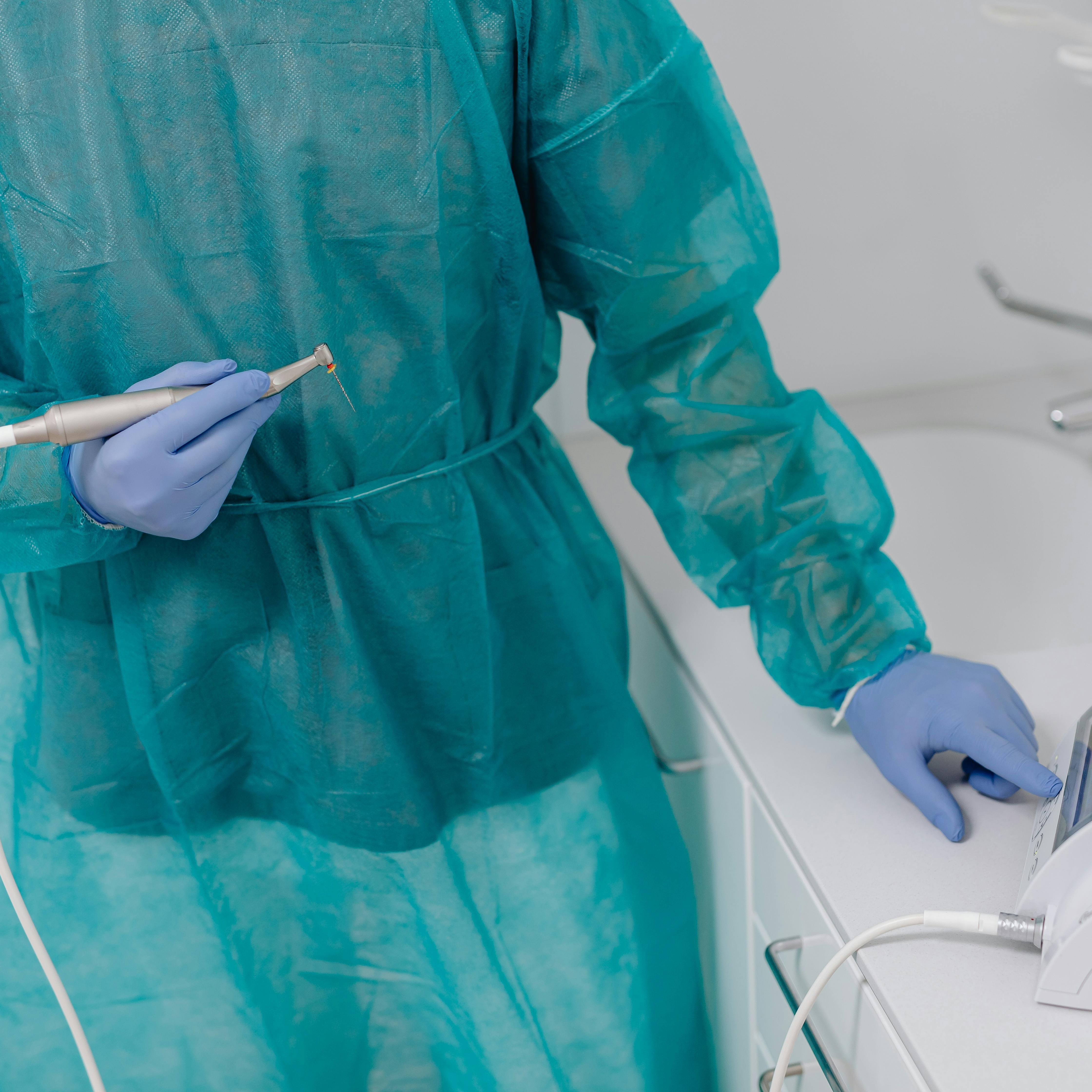 Summit Dental Care — gowned dental hygienist holding handpiece in a sunlit clinical treatment room