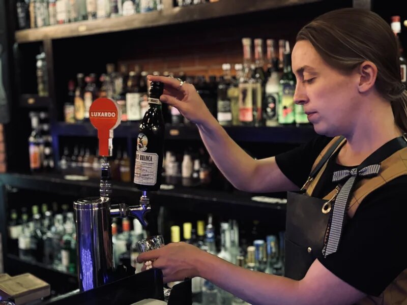 Bartender pouring a craft spirit behind the bar at La Casa del Sol