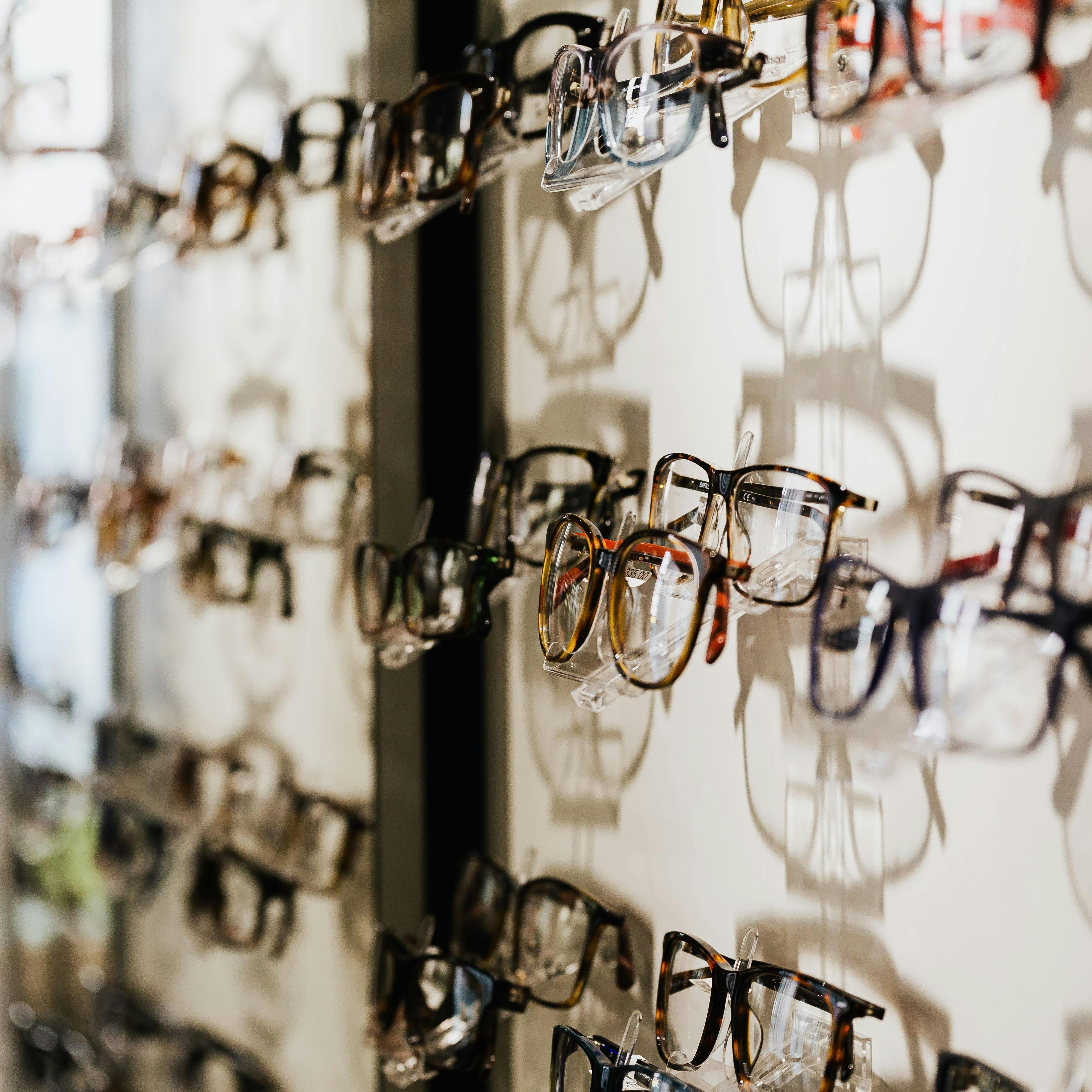 Wall of designer eyeglass frames from Ray-Ban, Oakley, Warby Parker and Lindberg