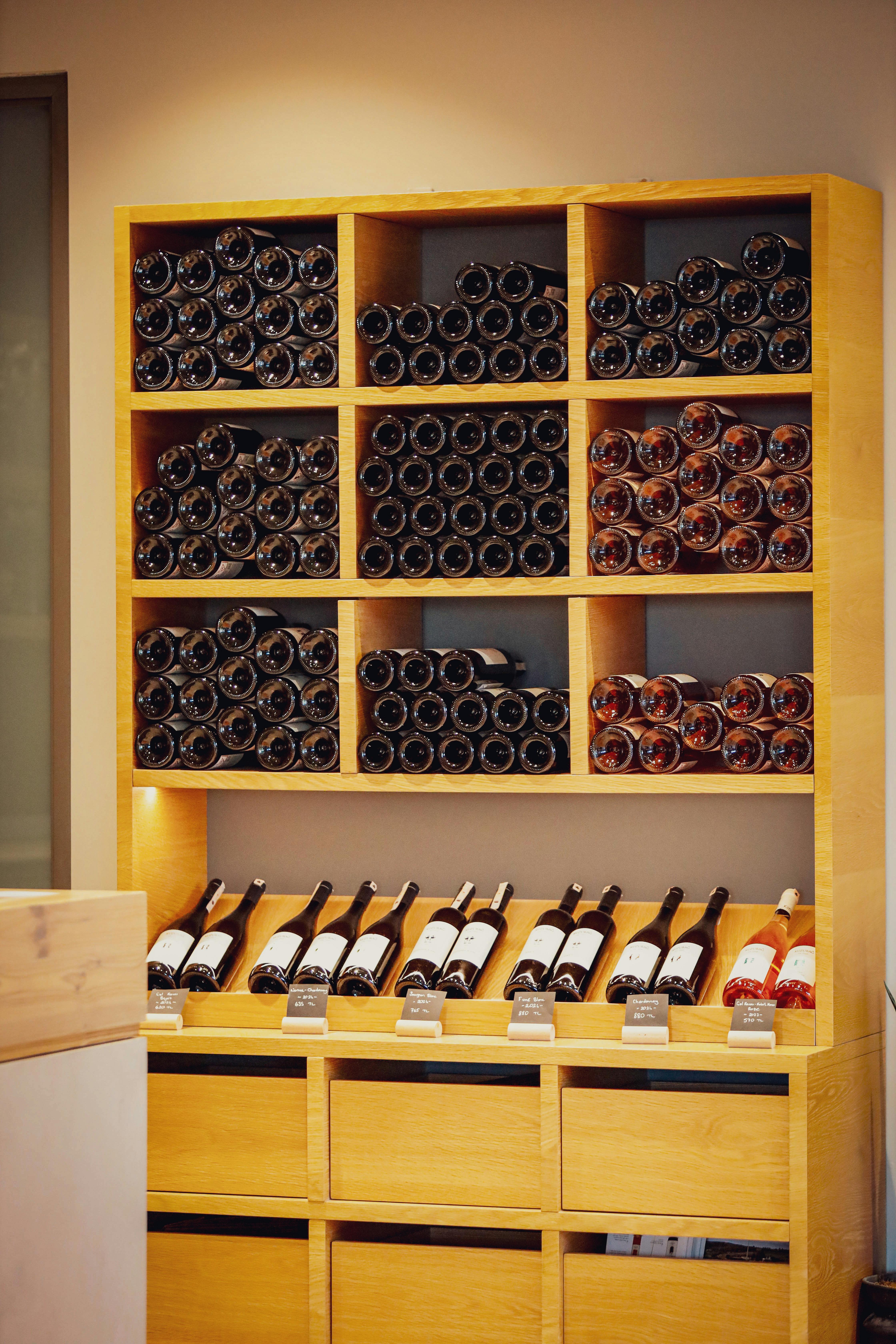 Stone wine cellar wall lined with horizontally stacked bottles, lit by a single warm sconce